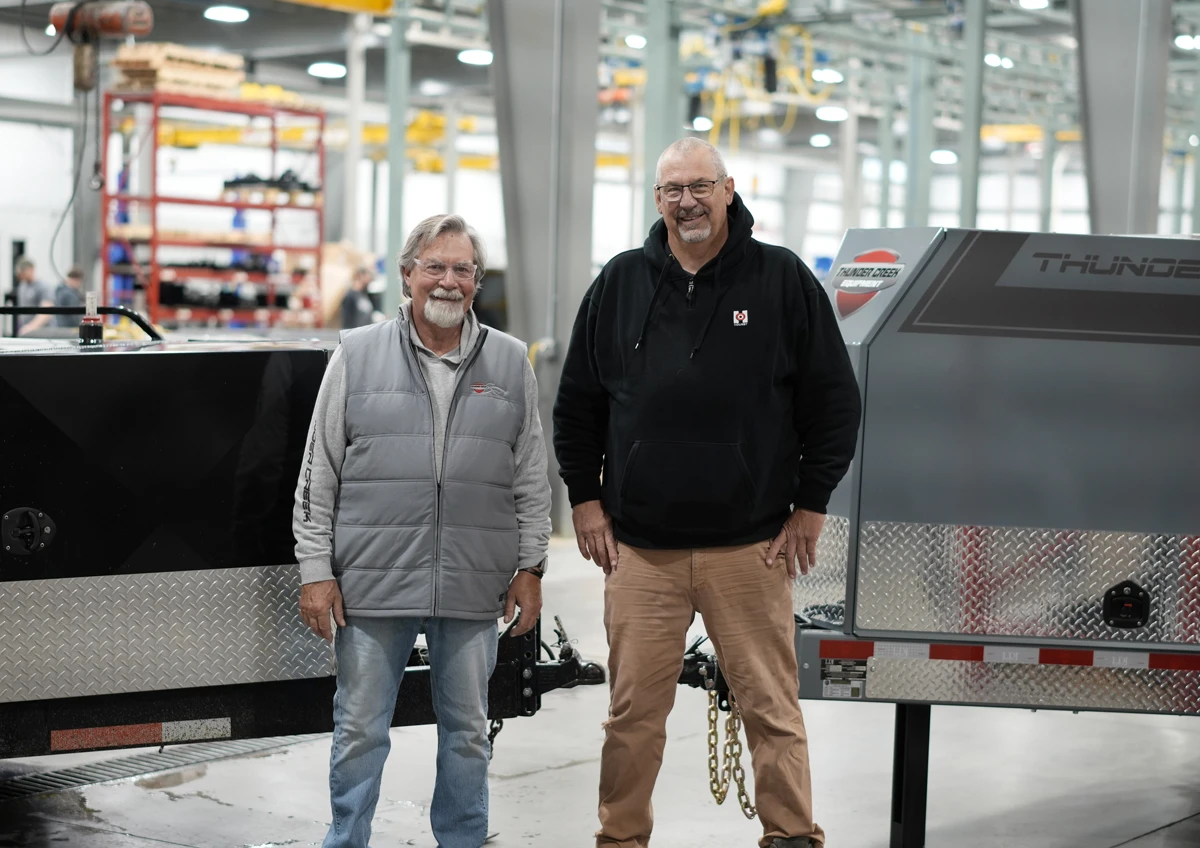 Two Men Standing in Front of The Original Thunder Creek Trailer and a New Thunder Creek Trailer